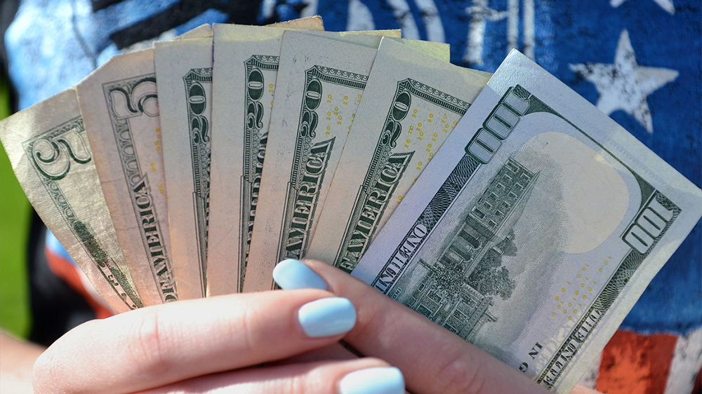 A female holds a handful of money cash currency