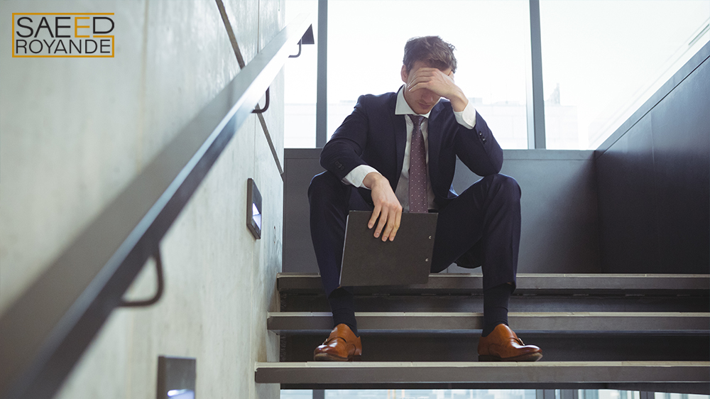 Depressed businessman with clipboard sitting