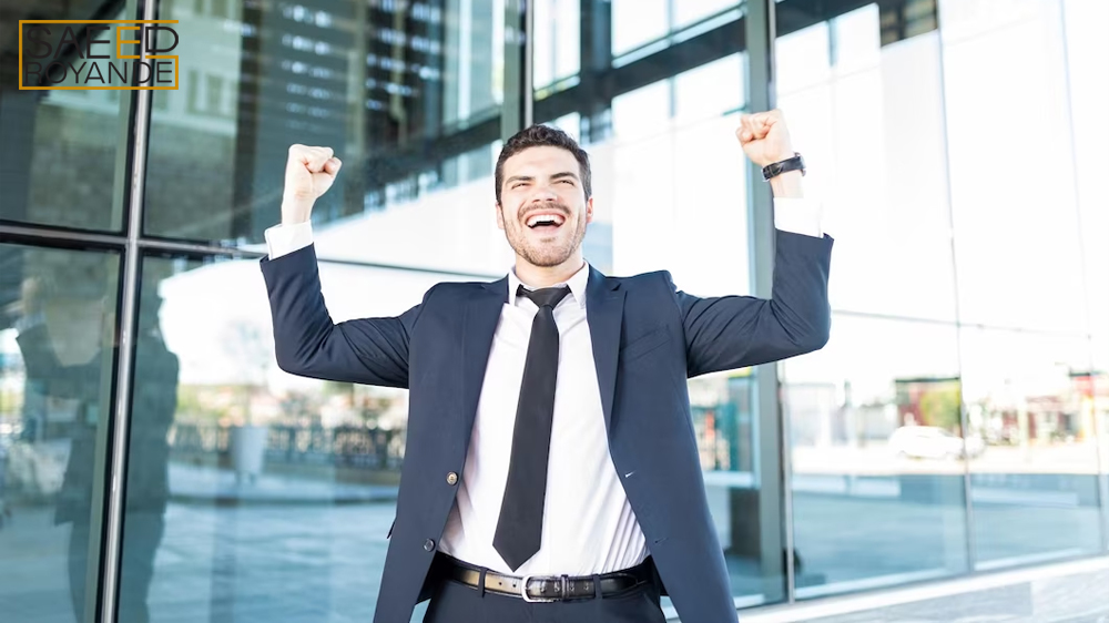 Cheerful hispanic businessman raising arms celebrating victory outside office building